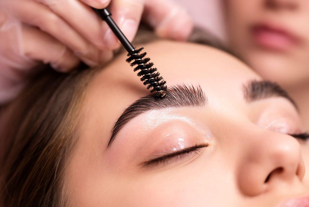 Brow artist brushing eyebrows upward during a lamination session